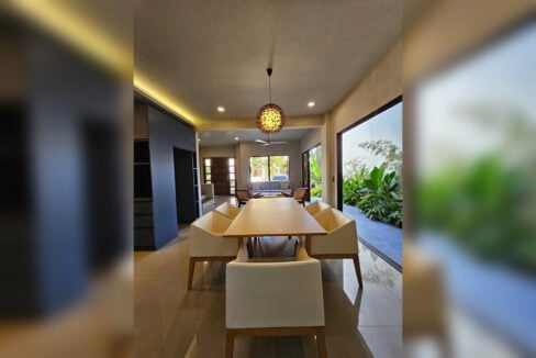 Dining area with a rattan pendant light, looking toward the living room
