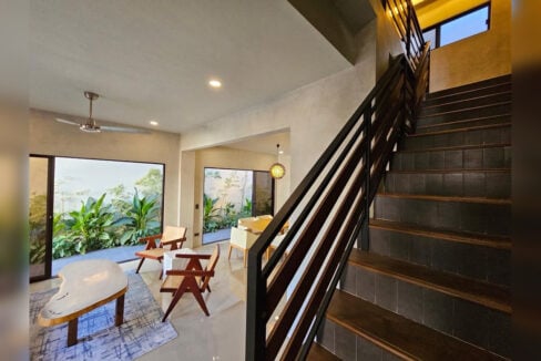 Staircase with a black steel railing beside the living room