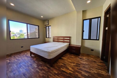 Master bedroom with parquet floors and a window looking toward the city