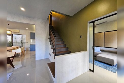 Staircase with timber treads and the ground-floor den behind a glass door