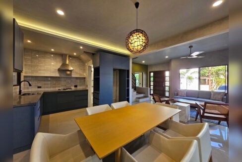 Dining table beside the kitchen with blue matte cabinets
