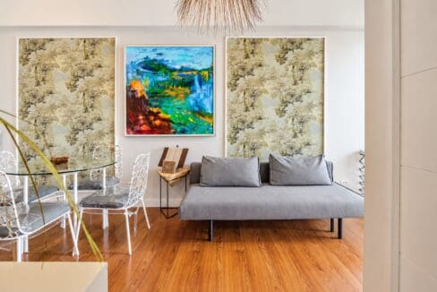 Grey fabric sofa and dining set against framed botanical wall panels and abstract artwork