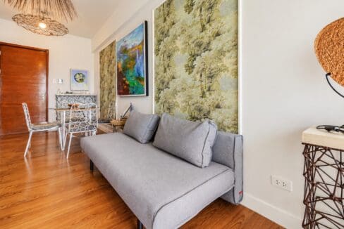 Sofa and dining area with woven pendant lights, looking toward the unit entrance
