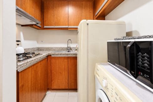 Kitchen with wood-grain cabinets, granite counters, gas cooktop, refrigerator, microwave and front-load washing machine
