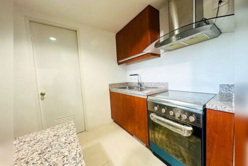 Kitchen with wood-grain cabinets, granite counters, range with oven and chimney hood