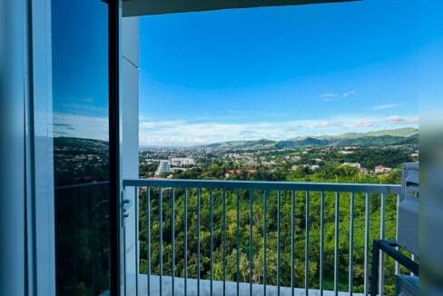 Balcony view over the treetops to the Cebu City skyline and mountains from Marco Polo Residences