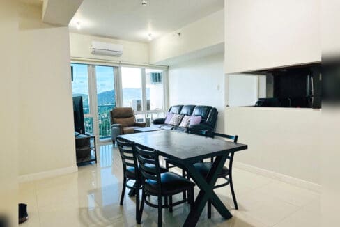 Dining table with four chairs, with the living area and mountain views beyond
