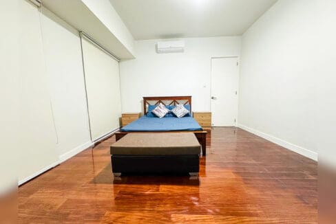 Master bedroom with timber bed, two bedside chests and upholstered bench on hardwood floor