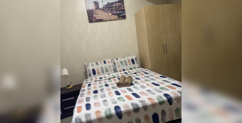 Bedroom with double bed, wooden wardrobe and bedside lamp