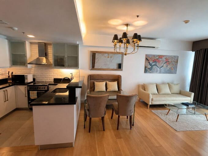 Furnished 1BR condo for sale at Park Point Residences, with the kitchen opening to the dining set under a black-shade chandelier