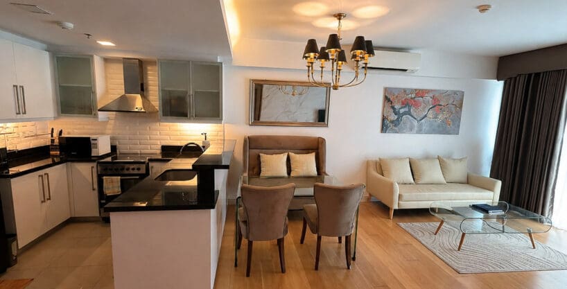Furnished 1BR condo for sale at Park Point Residences, with the kitchen opening to the dining set under a black-shade chandelier
