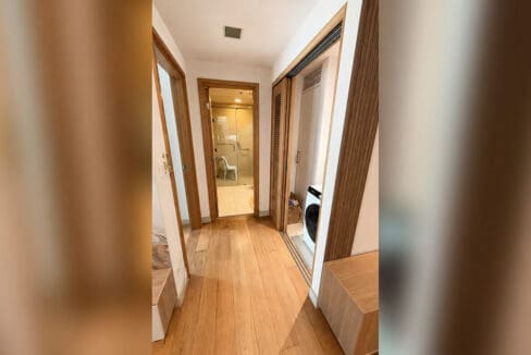 Hall between the bedroom and bathroom, with the laundry closet and washer behind louvered doors