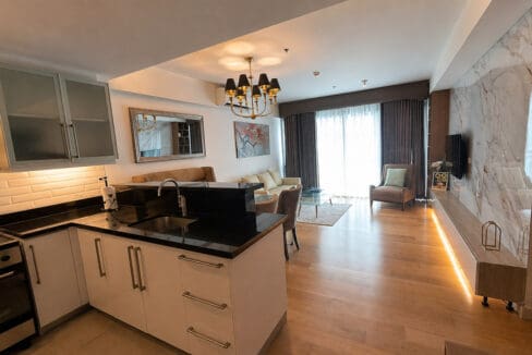 Kitchen peninsula in black granite, with the living area and the balcony doors beyond
