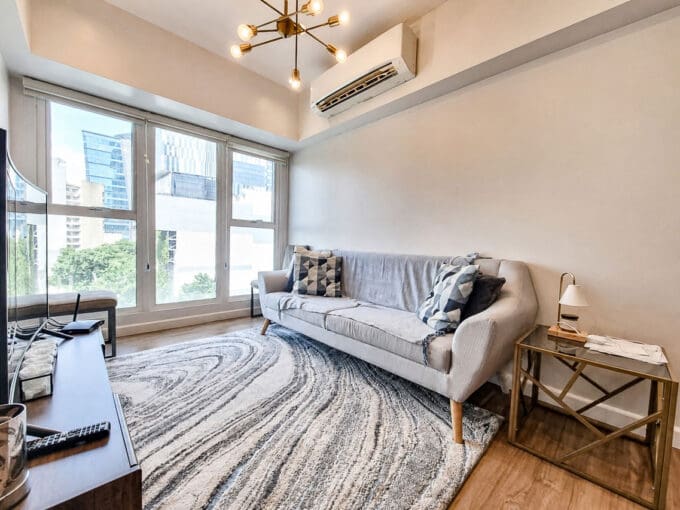 Living area with city views through floor-to-ceiling windows in the 2BR condo at Solinea Tower 3