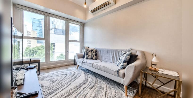 Living area with city views through floor-to-ceiling windows in the 2BR condo at Solinea Tower 3