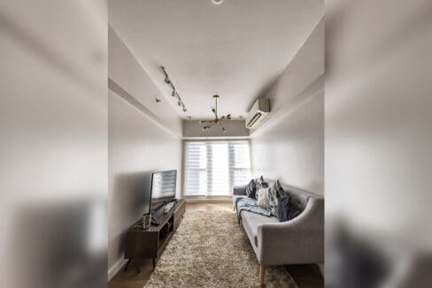 Living area with media console and roller blinds in the 2BR condo at Solinea Tower 3
