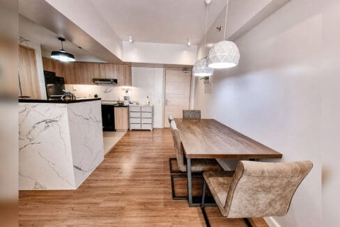Dining area seating four beside the marble-clad kitchen peninsula in the 2BR condo at Solinea Tower 3