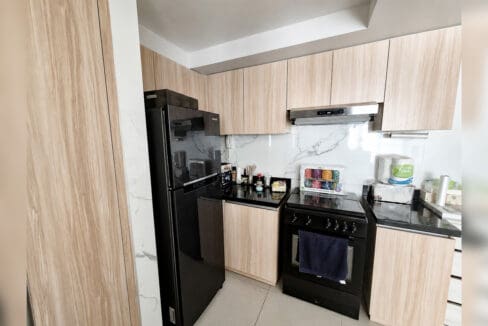 Kitchen with timber cabinets, range, and overhead hood in the 2BR condo at Solinea Tower 3