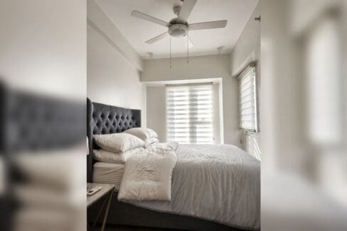 Bedroom with tufted headboard, ceiling fan, and roller blinds in the 2BR condo at Solinea Tower 3