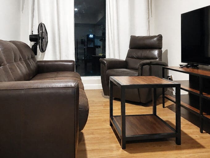 Living area with leather sofa, recliner, and wall-mounted flatscreen TV in the 2BR corner unit at Solinea Tower 3