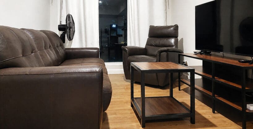 Living area with leather sofa, recliner, and wall-mounted flatscreen TV in the 2BR corner unit at Solinea Tower 3