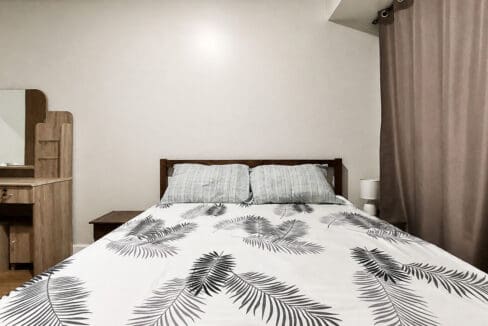 Main bedroom with timber headboard and dressing table in the 2BR corner unit at Solinea Tower 3