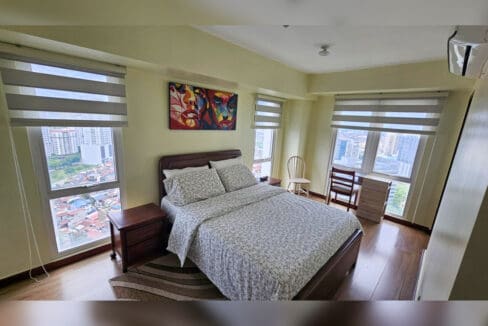 Corner bedroom with queen bed, bedside tables, study desk and zebra blinds