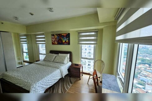 Bedroom with windows on two sides, sliding wardrobe and city views