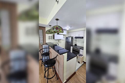 Breakfast bar with slatted timber front, two bar stools and black granite counter
