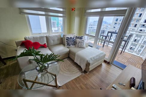 Sectional sofa and glass coffee table beside the balcony door with city views