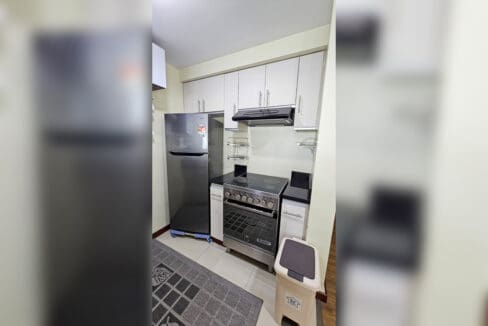 Kitchen with refrigerator, electric range with oven, range hood and white upper cabinets