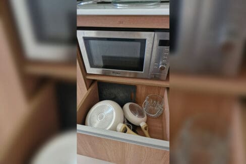 Kitchen storage with microwave and cookware included in the 2BR at Soltana Nature Residences