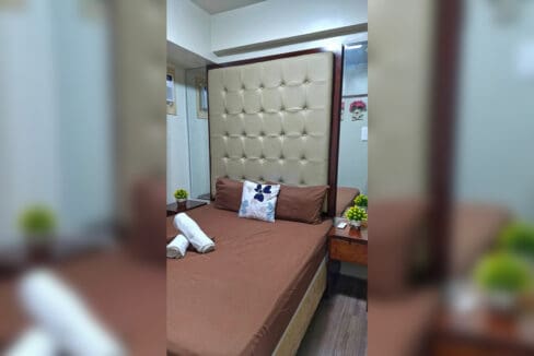 Main bedroom with a tall tufted headboard in the 2BR at Soltana Nature Residences