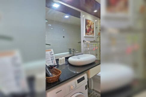 Bathroom with vessel sink, stone counter, and washing machine in the 2BR at Soltana Nature Residences