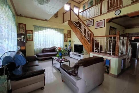 Living room under a double-height ceiling with the staircase open to the landing above