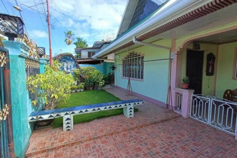 Brick-paved forecourt, lawn and covered porch inside the gated frontage