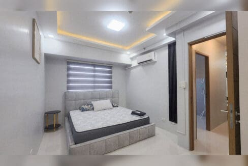 Bedroom with upholstered bed, cove-lit ceiling, zebra blind and split-type air conditioning