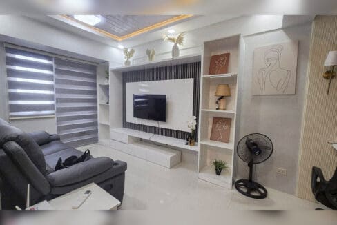 Built-in TV wall with slatted panelling and open shelving beside the recliner sofa