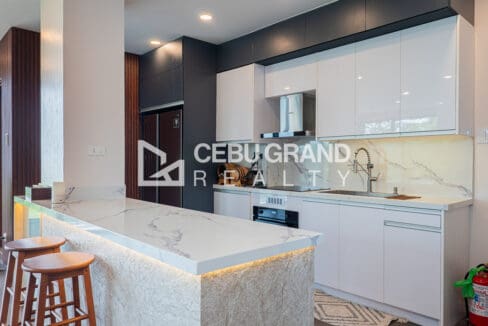 Kitchen with a marble waterfall peninsula, white gloss cabinetry and a built-in oven