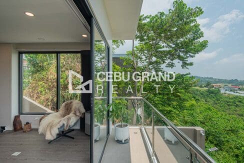 Glass-railed balcony opening off the interior to the hillside outlook
