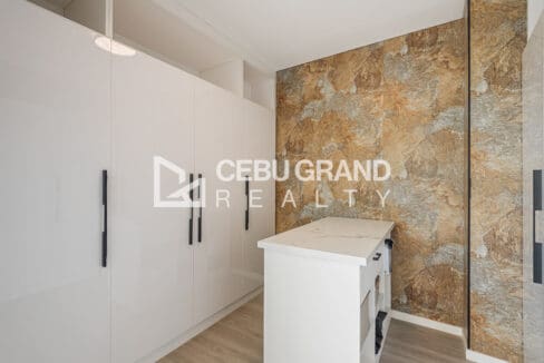 Walk-in dressing room with gloss cabinetry and a stone feature wall