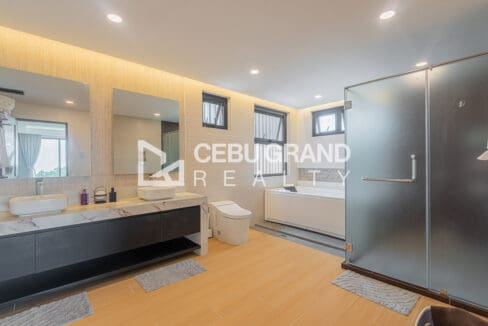 Master bathroom with twin stone-topped vanities, a soaking tub and a smart toilet