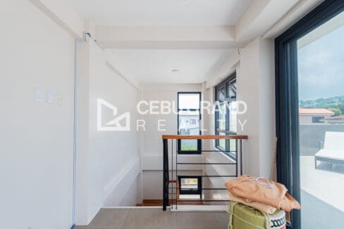 Top landing beside the stair, opening through sliding glass to the roof deck