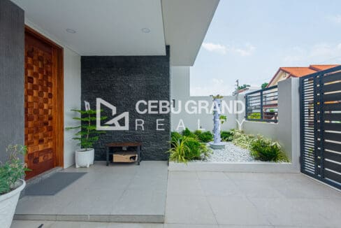 Entry court with a woven timber door, dark stone feature wall and a planted water feature