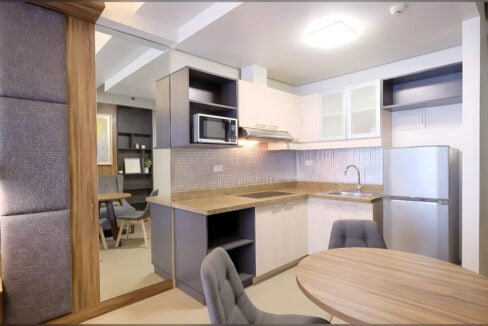L-shaped kitchen with granite counter, microwave and range hood in the Asia Premier studio