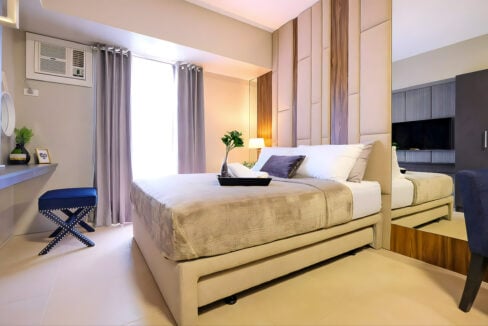 Bed with pull-out trundle, curtained window and window-type aircon in the Avida Riala Tower 1 studio