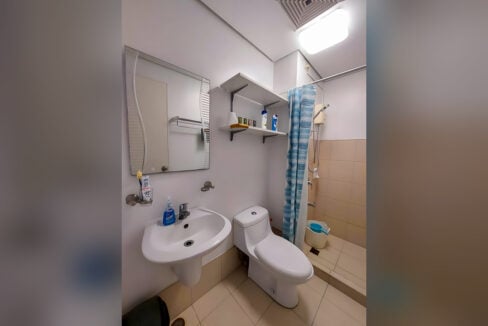 Bathroom with wall-hung sink, mirror, open shelves and shower with water heater at Avida Tower 2