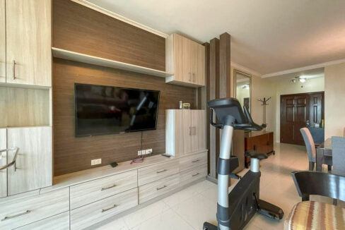 Built-in media wall with wood-grain cabinets, drawers and a wall-mounted TV