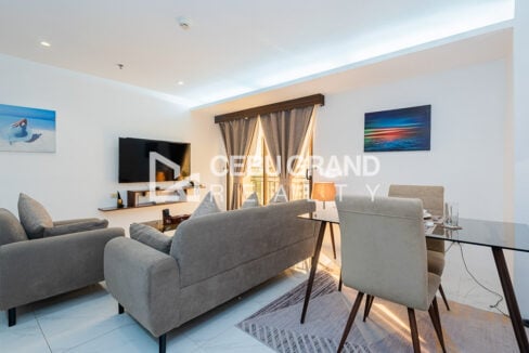Grey sofa set, wall-mounted TV and glass dining table under cove lighting