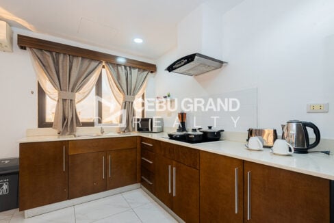L-shaped kitchen with wood cabinets, induction cooktop, range hood and microwave